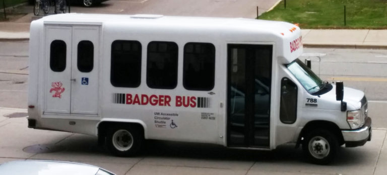 Example image of what the accessible circulator shuttle may look like. A small white bus with "Badger Bus" written on the side. A sign on the side reads "UW Accessible Circulator Shuttle."