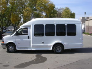 Image of the left side of the white bus. UW decals are visible.