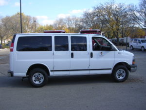 Image of a white 8 passenger van with UW decals.