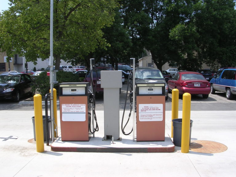 Close-up image of two gas pumps in the middle of a parking lot.