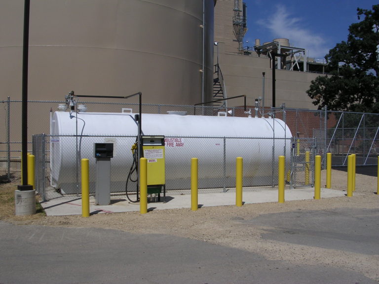 Close up shot of a large diesel fuel cylinder surrounded by yellow parking barriers.