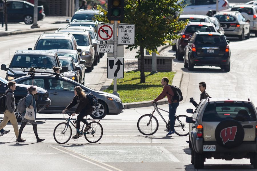 Seen in silhouette, pedestrians and students walk across S. Park Street at the intersection of University Avenue in the heart of the University of Wisconsin-Madison campus during autumn on Nov. 3, 2016.