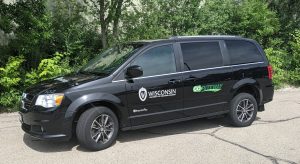 Image of the accessible circulator shuttle vehicle -- a black van with the UW-Madison logo in white and black and the vendor's logo on the vehicle's doors. Click image to enlarge.