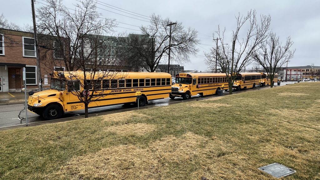 Photo of three yellow school buses parked near the Kohl Center for a WIAA Boys' Basketball tournament. Photo by Jon Kjarsgaard.